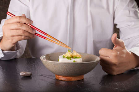 Japanese tofu, a man prepare to eat Japanese cold tofu on dining table with chopsticksの写真素材