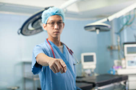 doctor said, a male doctor point at the camera in the operation room with all equipmentの写真素材