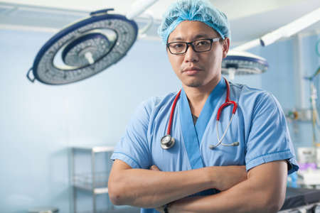 operation doctor, a male surgeon doctor crossing his arm in the operation room with equipmentの写真素材