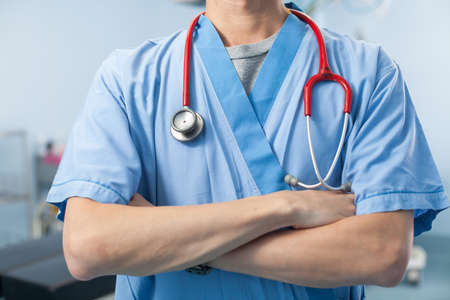 operation doctor, a male surgeon doctor crossing his arm in the operation room with equipmentの写真素材