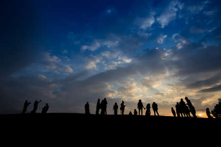 Silhouette of people waiting for sun rise at the mountain peak with dramatic sky, Thailandの写真素材