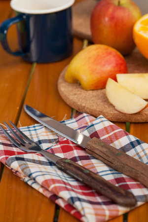 Various wood made utensils, knife,fork,spatula put on decorated table with fruit and flowerの写真素材