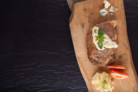 A prepared piece of steak cut with blue cheese sauce on dining table utensils decorated.の写真素材