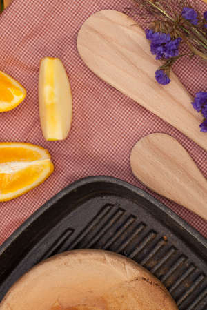 Wood made spatula and pancake on a steel pan put on decorated table with fruit and flower