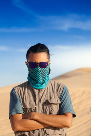 An Asian Male tourist traveling in windy white sand dunes at Muine desert, Phan thiet, Vietnamの写真素材