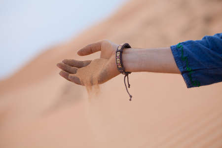 Single hand holding sand in desert let it running through fingers, Muine sand dunes, Vietna