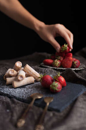 Strawberry cut snack filling strawberry cream decorated with a female hand picking fresh strawberry fruitの写真素材