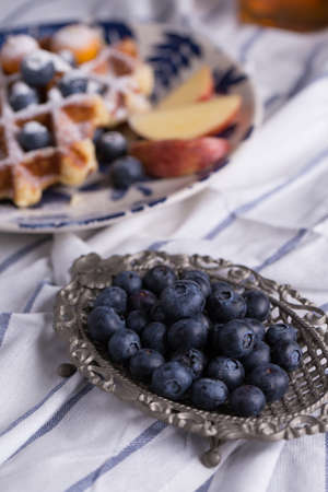 A beautiful silver dish with blueberry and a dish of blueberry waffle decorate with appleの写真素材