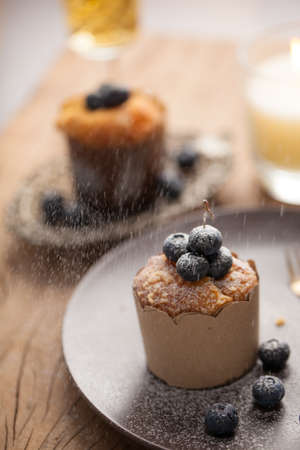 Blueberry muffin in a dish decorated with fresh blueberry and white candle on the tableの写真素材