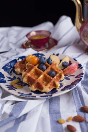 Blueberry apple waffle with honey set on a dish decorated with fresh blueberry, appleの写真素材