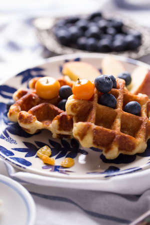 Blueberry apple waffle with honey set on a dish decorated with fresh blueberry, appleの写真素材
