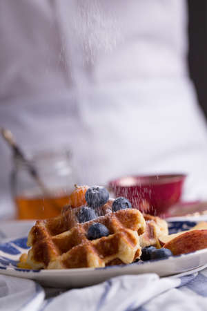 Blueberry apple waffle with honey set on a dish decorated with fresh blueberry, apple, tea pot set ready to serve.の写真素材