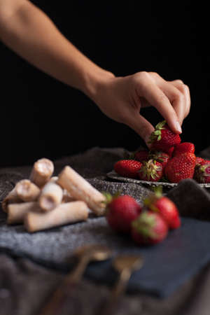 Strawberry cut snack filling strawberry cream decorated with a female hand picking fresh strawberry fruitの写真素材