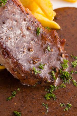 A dish of beef steak served with pepper brown sauce, spinach sautÃ© and french fries in a decorated dish.の写真素材