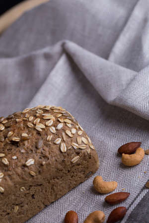 Whole grain bread put on kitchen napkin decorated with almond with a chef holding dough roller at the background.の写真素材