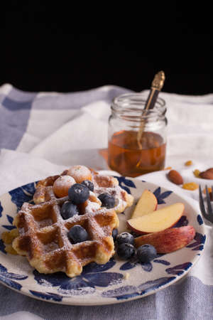 Blueberry apple waffle with honey set on a dish decorated with fresh blueberry, apple, tea pot set ready to serve.の写真素材