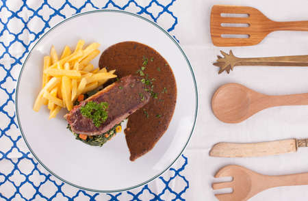 A nice dish of beef steak served with mashed potato,lemon, saute spinach and sauce on background...