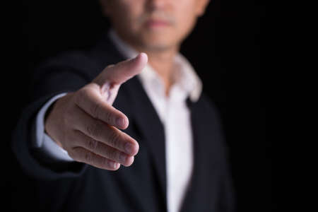 A business man wearing black suit giving one hand for shaking in cooperate look.の写真素材