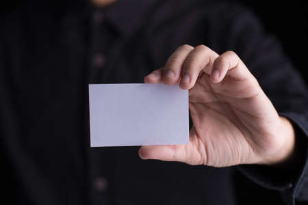 A man in business black suit holding a white blank business card,name card.の写真素材