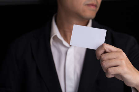 A man in business black suit holding a white blank business card,name card.の写真素材
