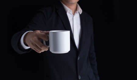 A business man in casual black suit holding a cup of coffee.