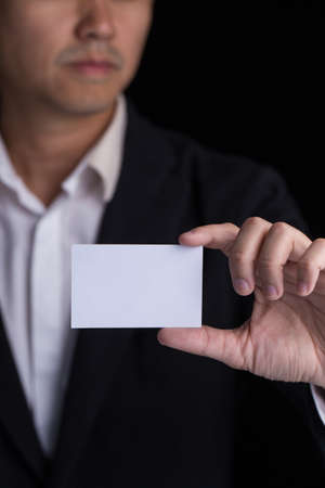 A man in business black suit holding a white blank business card,name card.の写真素材