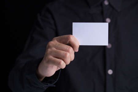 A man in business black suit holding a white blank business card,name card.