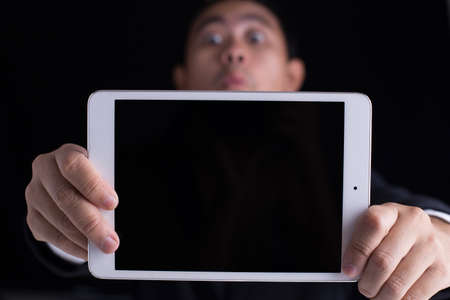 A business man showing black screen of touch pad with copy space and funny face.