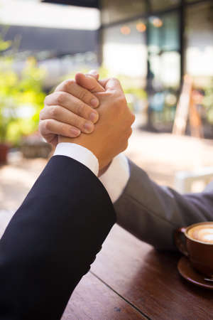 Two business man arm wresting while having coffee at the coffee shop.の写真素材