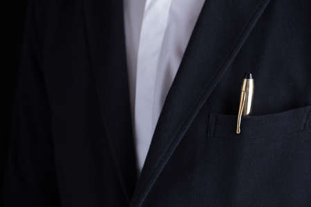 A man in black suit with a gold fountain pen for sign the contract in suit pocket.の写真素材