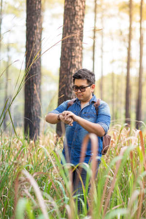 A man checking something on his watch or waiting for someone in the pine forest, Thailandの写真素材