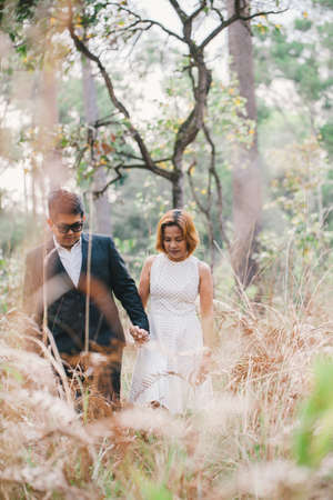 A couple in formal dress black suit and white dress romance in the pine forest before wedding, Thailandの写真素材