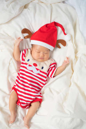 Asian baby boy wearing red Santa Claus outfit with reindeer hat.の写真素材