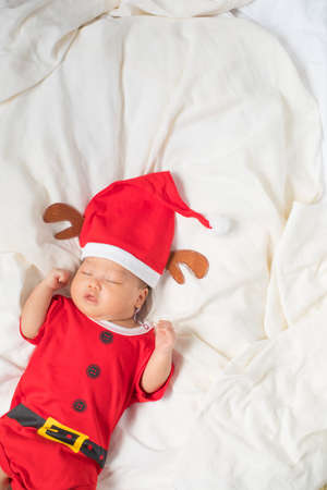 Asian baby boy wearing red Santa Claus outfit with reindeer hat.の写真素材