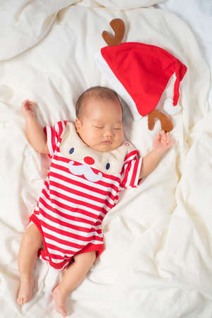 Asian baby boy wearing red Santa Claus outfit with reindeer hat.の写真素材