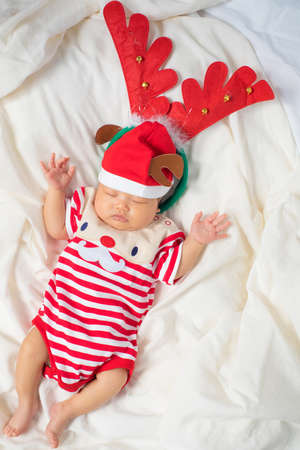 Asian baby boy wearing red Santa Claus outfit with reindeer hat.の写真素材