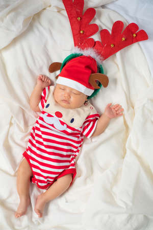 Asian baby boy wearing red Santa Claus outfit with reindeer hat.の写真素材