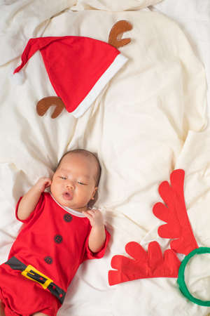 Asian baby boy wearing red Santa Claus outfit with reindeer hat.の写真素材
