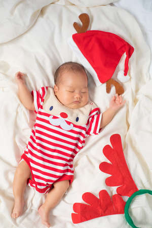 Asian baby boy wearing red Santa Claus outfit with reindeer hat.の写真素材