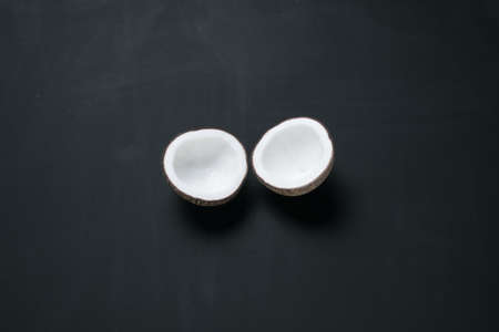 Coconut shell breaking to two parts on blackboard background.の写真素材