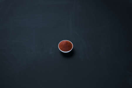 Thai red curry paste in a small bowl isolated on blackboard background.の写真素材