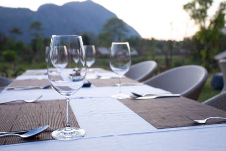 A fine dinner table set with high wine glass and utensils on the table with mountain view.の写真素材