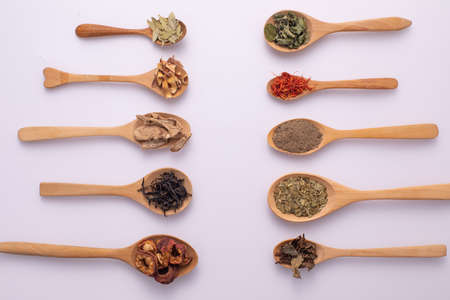 Various kind of dried leaves, fruit and flower put in many kind of wooden spoons on white background.の写真素材