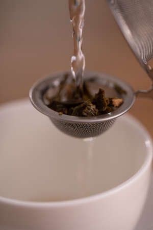 Tea diffuser close up to texture of tea leaf ingredient with pouring hot water.の写真素材