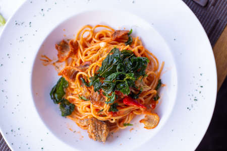 A dish of pasta with red spicy sauce and fried Snakeskin gourami fish on top with deep fried basil in Thai style.の写真素材