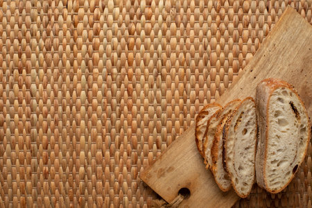 Cut bread showing air texture of flour on wood block with weave background and copy space.の写真素材