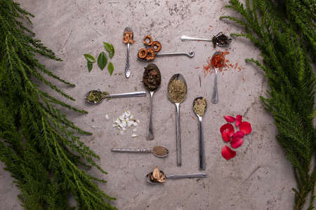 Various ingredient of tea leaf put in many kind of spoon with many kind of herbs and flowers decorated.の写真素材