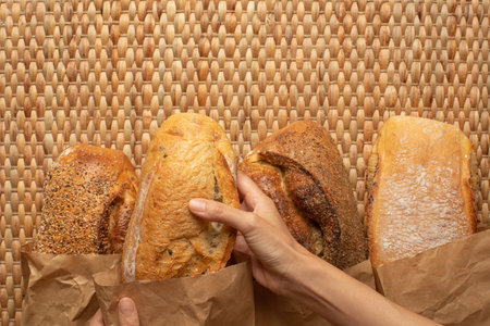 A female hand picking a loaf of bread from various kind of bread on weave grass background.