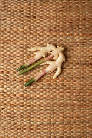 Ginger roots isolated on brown wallpaper showing texture of weave dried water hyacinth placemat.の写真素材
