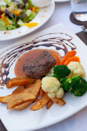 Beef steak brown sauce served with vegetable and fries in a nice dish.の写真素材